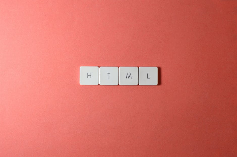 A close-up image shows four white rectangular keyboard keys placed on a smooth, matte coral-pink surface. The keys are arranged in a straight horizontal line and have black capital letters printed on